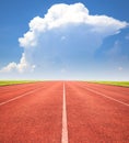 Red running track over blue sky and clouds Royalty Free Stock Photo