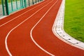 Red running track with white lines in outdoor sport stadium, side is a field and park. Backgrounds and rubber. Royalty Free Stock Photo