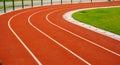 Red running track with white lines in outdoor sport stadium, side is a field and park. Backgrounds and rubber texture Royalty Free Stock Photo