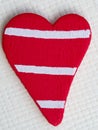 Red rustic wooden heart shape with painted white stripes, close-up