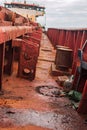 Red rusty metal on board the dry cargo ship. Abandoned shipwrecked vessel. View from the deck.