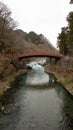 Red sacred wooden bridge in Nikko Japan with a river and cloudy sky