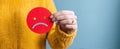 The red sad face symbol held by a person in a yellow sweater..AI generated image Royalty Free Stock Photo