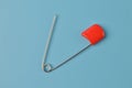 Red safety pin isolated on a blue background Royalty Free Stock Photo