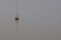 A red sailboat sits in a cove in fog Royalty Free Stock Photo