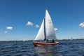 A red sailing boat on the Kagerplassen with 2 people sailing in the South-Holland municipality of Warmond