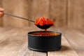 Red salmon caviar in a black tin can and a black spoon full of caviar on a wooden background Royalty Free Stock Photo