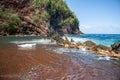 Red Sand Beach, Maui in in Hawaiian. Ocean waves and rock. Royalty Free Stock Photo