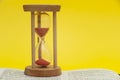 Red sand hourglass on top of open Holy Bible in the Book of the Prophet Ezekiel chapter 7 verse 7. Isolated on yellow background Royalty Free Stock Photo