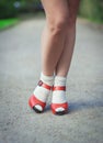 Red sandals with white socks on girl legs in fifties style