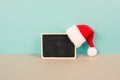 Red Santa Claus hat hanging on a chalkboard, greeting card for christmas, copy space for text, winter season Royalty Free Stock Photo