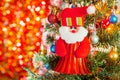 Red Santa doll is an ornament on a Christmas tree against light background for Christmas Day and New Year holidays background. Royalty Free Stock Photo