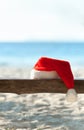 Red Santa's hat on wooden bench on the beach