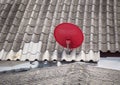 Red satellite dish is attached on top of roof. Royalty Free Stock Photo