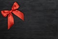 Red satin ribbon with bow over black background. Royalty Free Stock Photo