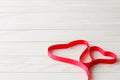 Red Satin Ribbon in Shape of Two Hearts on Wooden Background Royalty Free Stock Photo