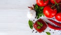 Red sauce or ketchup, tomatoes, garlic, basil, parsley and red hot pepper on a wooden white background. Close-up. Royalty Free Stock Photo