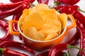 In a red saucepan potato chips with spices, surrounded by red peppers, spicy snack, fast food concept Royalty Free Stock Photo