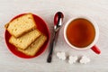 Saucer with pieces of muffin, spoon, cup of tea, pieces of sugar on table. Top view Royalty Free Stock Photo