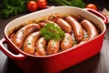 red sausages drenched in homemade frothy beer onion marinade in a pyrex dish