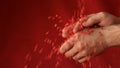 Red heart shaped confetti fall in man's hands