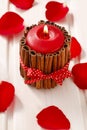 Red scented candle decorated with cinnamon sticks. Rose petals a Royalty Free Stock Photo