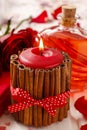 Red scented candle decorated with cinnamon sticks. Rose petals a Royalty Free Stock Photo