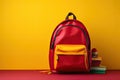 Red school backpack with books and stationery on table against yellow background Royalty Free Stock Photo