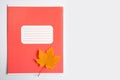 A red school notebook, magazine or diary and an autumn yellow maple leaf Royalty Free Stock Photo