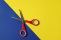 Red scissors and blue paper on yellow background, top view. Space for text Royalty Free Stock Photo