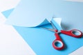 Red scissors and light blue paper on white background Royalty Free Stock Photo