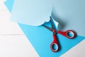 Red scissors and light blue paper on white wooden background, top view Royalty Free Stock Photo