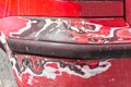 Red scratched car with damaged bumper paint and body in crash accident or parking lot Royalty Free Stock Photo