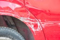 Red scratched car with damaged paint in crash accident or parking lot and dented metal body from collision Royalty Free Stock Photo