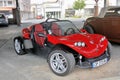A red Secma sports car on a parking