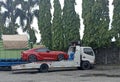 Red sedan being hauled away by a towing truck