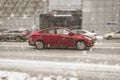 Red sedan Hyundai Solaris Accent fast speed driving on winter asphalt road during heavy snowfall