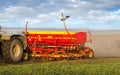 A red seeder, sowing in the field, cloud of dust. Agricultural tillage, prepare the land