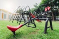 Red seesaw in the playground. Playground equipment for children to play. Plastic seesaw or teeter-totter, swing, and slide at Royalty Free Stock Photo