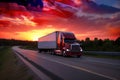 A red semi truck going down an interstate highway with sunrise ang America flag