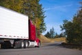 Red semi truck rig and trailer on autumn convoluted highway Royalty Free Stock Photo