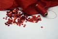 Red sequins, spool of red thread, needle on rippled red silk background. Royalty Free Stock Photo