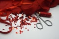 Red sequins, spool of red thread,needle and scissors on rippled red silk background. Royalty Free Stock Photo
