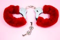 Red sexy fluffy handcuffs with keys on a pink background Royalty Free Stock Photo