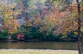 Red shed on bank of pond with autumn colors