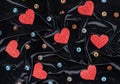 Red shining hearts and multicolored glass balls on a black velvet. Valentine`s day concept