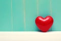 Red shiny heart on vintage teal wood