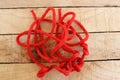 Red ship ropes pile tied to knot isolated on wooden background closeup. Royalty Free Stock Photo