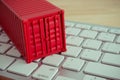 Red shipping cargo container on white keyboard computer and wooden table background. E-commerce or online shopping, logistic Royalty Free Stock Photo