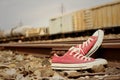 Red shoes leaning on the train tracks.